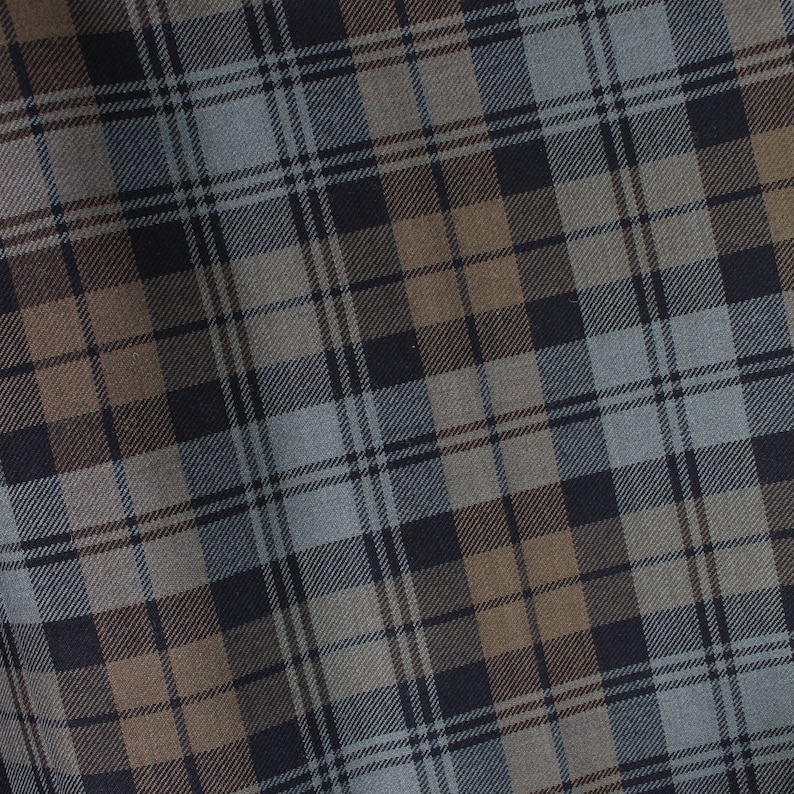 May include: A close-up of a fabric with a plaid pattern in shades of brown, grey, and black.
