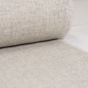 May include: A close-up of a soft, white and gray fuzzy fabric. The fabric is rolled up and the texture is visible.