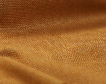 May include: Close-up of a textured fabric in a warm, golden-brown hue. The weave is visible, creating a subtle pattern. The fabric is folded, showing depth and dimension. Ideal for apparel or home decor.
