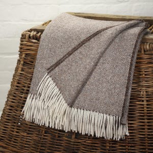 Op de afbeelding: Een set van drie keramische mokken met een gespikkelde, crèmekleurige glazuur. Elke mok heeft een ander handgeschilderd ontwerp: een blauw en groen blad, een gele bloem en een rode bes. De mokken hebben een eenvoudig, modern ontwerp.