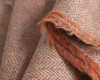 May include: Close-up of a soft, orange and white herringbone patterned fabric. The fabric has a fuzzy texture and is folded over.