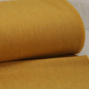 May include: A close-up of a roll of yellow fabric with a textured weave.