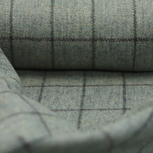 May include: Close-up of a blue and gray plaid fabric with a subtle texture. The fabric is folded in half, revealing the pattern on both sides.