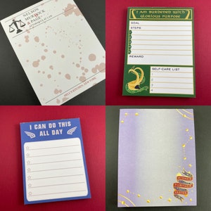 May include: Four different notepad designs. The first notepad is white with brown splotches and the text "NELSON MURDOCK & PAGE ATTORNEYS AT LAW HELL'S KITCHEN, NEW YORK". The second notepad is green with the text "I AM BURDENED WITH GLORIOUS PURPOSE GOAL STEPS 1 2 3 4 5 REWARD SELF-CARE LIST 1 2 3 4". The third notepad is blue with the text "I CAN DO THIS ALL DAY" and stars. The fourth notepad is purple with gold stars and the text "HIGHER FURTHER FASTER".