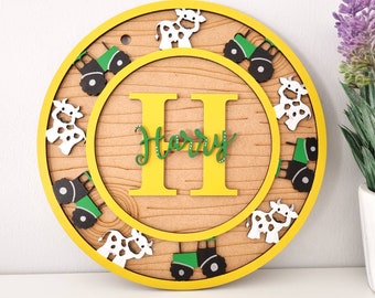 May include: A yellow and brown wooden round sign with a white and green tractor, cows, and the name "Harry" in yellow letters.