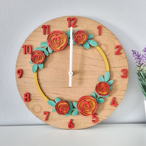 May include: A wooden clock with a floral design. The clock face has red numbers and a white background. The floral design is made of red and green paper flowers.
