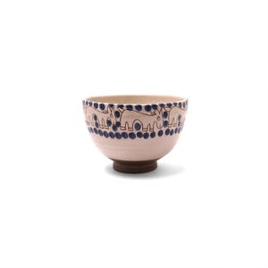 May include: A ceramic bowl with a light pink exterior and a dark brown base. The rim features a repeating pattern of blue animal figures and dots. The bowl is a decorative piece, suitable for serving or display.