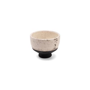 May include: A small white ceramic bowl with a black base. The bowl has a speckled white glaze and a black rim.