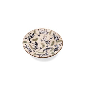 May include: A white ceramic bowl with a blue and black spotted animal design. The bowl is decorated with green leaves and has a slightly raised rim.