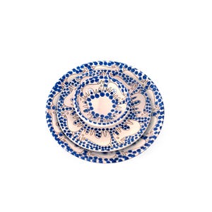 Peut inclure: Un ensemble de trois assiettes en céramique blanche avec des motifs bleus et bruns. Les assiettes sont empilées les unes sur les autres, la plus petite étant en haut. Les assiettes présentent un motif répétitif d'animaux stylisés et de points bleus.