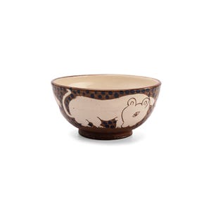 May include: A brown ceramic bowl with a white glaze and a hand-painted design of a white animal with blue eyes. The animal is walking on a brown background with blue dots.