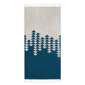 Op de afbeelding: Een blauw en wit geometrisch tapijt met een franje rand. Het tapijt heeft een witte achtergrond met een blauw geometrisch patroon van driehoeken.