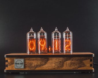 May include: A wooden digital clock with four glass tubes displaying the time as 09:12 in bright orange. The clock sits on a dark surface, with the brand name "WIXIE STAR" visible on the front.
