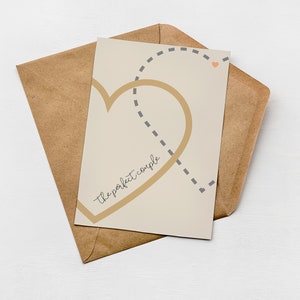 Greenwich Paper Studio, neutral minimal style love card with two interlinking hearts and 'the perfect couple' text, styled laying flat on a brown Kraft envelope.