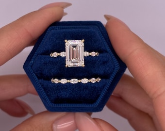Könnte beinhalten: Ein Satz aus drei goldenen Ringen mit Diamanten. Der mittlere Ring hat einen großen Diamanten im Smaragdschliff, während die beiden kleineren Ringe kleinere runde Diamanten haben.