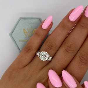 Anello di fidanzamento con diamante da laboratorio taglio ideale rotondo a tre pietre, certificato IGI, colore E, purezza VVS2, diamanti laterali trapezoidali, oro bianco 18 carati