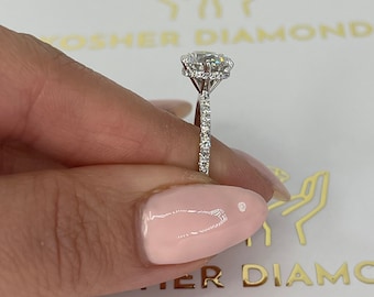 May include: A silver engagement ring featuring a round centre stone with a halo of smaller diamonds. The band is also set with smaller diamonds.
