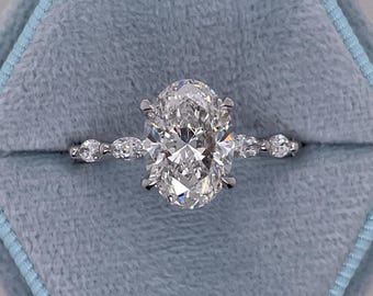 May include: A silver engagement ring with an oval-shaped diamond center stone and smaller diamonds set in a pave band.