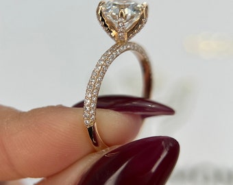 May include: A gold engagement ring with a large, round, clear centre stone and a pave diamond band.
