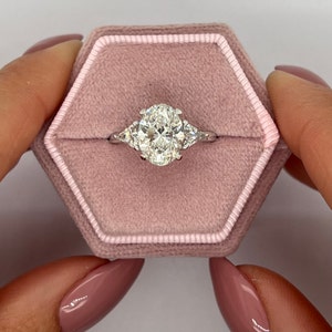 Anillo de compromiso de tres diamantes cultivados en laboratorio, talla ovalada, color D, claridad VVS2, de 2,5 quilates y diamantes laterales a juego de talla trillón, oro blanco de 18 k.