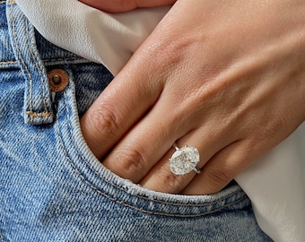 Può includere: Primo piano di una mano che indossa un anello d'argento con un grande diamante di forma ovale. L'anello è sull'indice della mano, che riposa nella tasca di un paio di jeans blu.