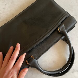 May include: A black leather briefcase with gold hardware and a single top handle.