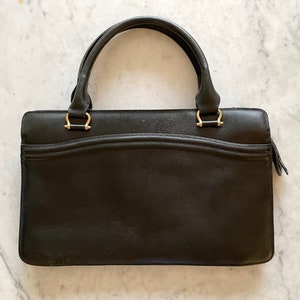 May include: A black leather handbag with gold hardware and a top handle.