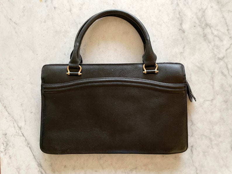 May include: A black leather handbag with gold hardware and a top handle.