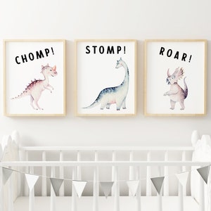 May include: Three framed watercolour illustrations of dinosaurs with text overlays. The first frame shows a pink dinosaur with the text "CHOMP!" The second frame shows a blue dinosaur with the text "STOMP!" The third frame shows a purple dinosaur with the text "ROAR!"
