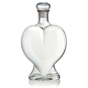 May include: A clear glass bottle shaped like a heart with a glass stopper. The bottle is empty.