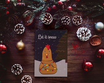 May include: A Christmas card with a brown chicken wearing a string of colorful lights. The card has a dark blue background with white snowflakes and the text "Let it snow".