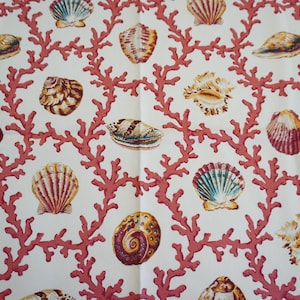 Puede incluir: Tela con un patrón repetido de conchas marinas y ramas de coral. Las conchas son en tonos marrones, amarillos y azules, mientras que el coral es de color rosa rojizo. El fondo es de color crema claro.