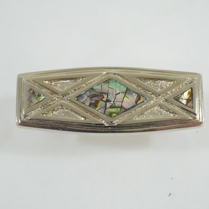 May include: Silver-toned rectangular belt buckle with an inlaid abalone shell design. The buckle features a geometric pattern with diamond and triangular shapes. The abalone shell has iridescent colors of green, blue, and gold.