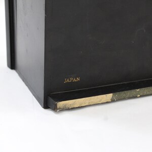 May include: Black wooden box with a gold label that reads "JAPAN".