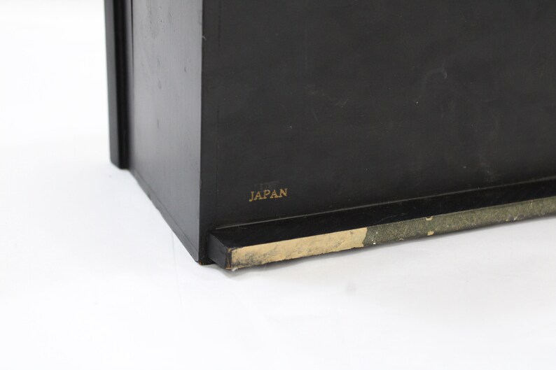 May include: Black wooden box with a gold label that reads "JAPAN".
