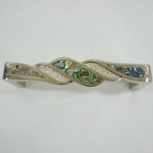 May include: A silver cabinet pull with a twisted design. The center features iridescent abalone shell and sparkling silver accents. The hardware is approximately 6 inches long.