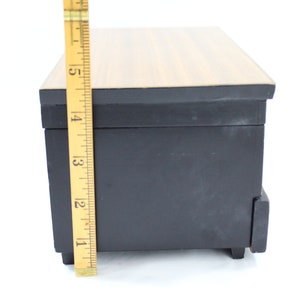 May include: A black wooden box with a woodgrain top and a small drawer. The box is approximately 10 cm tall.