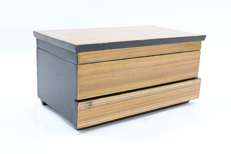 May include: A wooden jewellery box with two drawers. The top drawer is black with a wood grain pattern. The bottom drawer has a gold and black striped pattern.