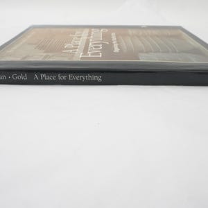 Może przedstawiać: Książka w twardej oprawie zatytułowana "A Place for Everything" autorstwa Wolfmana i Golda. Książka ma czarną okładkę z tytułem i nazwiskami autorów w kolorze białym. Grzbiet książki również wyświetla tytuł i autorów.