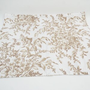 May include: White fabric with a brown floral pattern. The design features detailed botanical illustrations of flowers and foliage. The fabric is likely used for home decor or apparel.