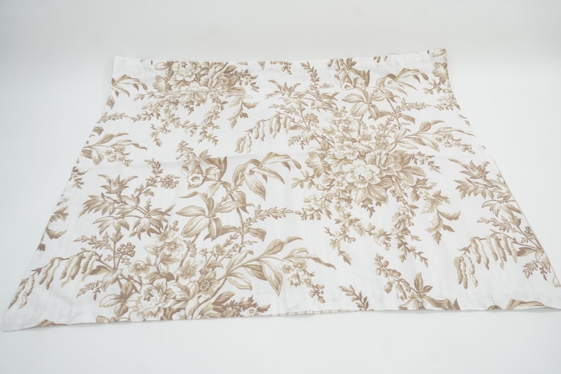 May include: White fabric with a brown floral pattern. The design features detailed botanical illustrations of flowers and foliage. The fabric is likely used for home decor or apparel.