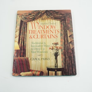 Puede incluir: Un libro titulado "Complete Book of Window Treatments & Curtains" de Carol Parks. La portada presenta una habitación con cortinas, una silla y una mesa con flores. El subtítulo del libro dice "Traditional & Innovative Ways to Dress Up Your Windows."