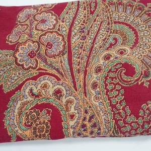 Peut inclure: Un coussin rectangulaire avec un fond rouge foncé et un motif cachemire détaillé dans des tons or, vert et bleu. Le design présente des éléments floraux et courbes, créant une apparence riche et texturée. Idéal pour la décoration intérieure.