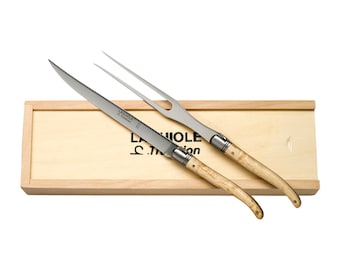 May include: A wooden box containing a carving knife and fork set with a natural wood handle. The set is made by Laguiole en Aubrac.