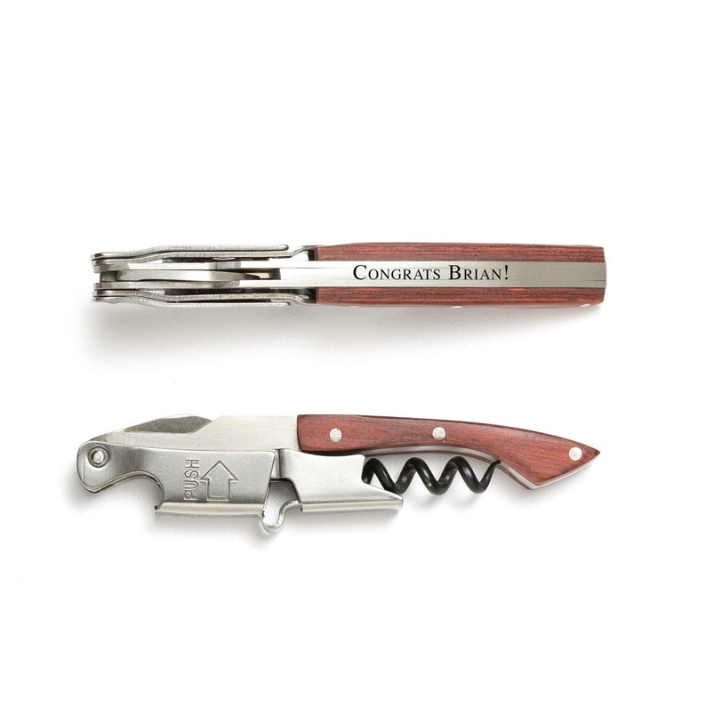 May include: A silver and wood corkscrew with a red wooden handle. The handle is engraved with the text "Congrats Brian!"