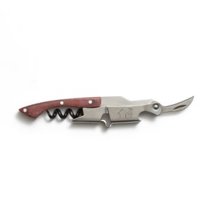 May include: A silver and wood corkscrew with a built-in bottle opener. The corkscrew has a wooden handle and a silver metal body. The bottle opener is located on the side of the corkscrew and has a small blade. The corkscrew is in the open position, with the corkscrew and bottle opener visible.