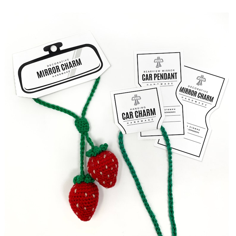 May include: A green crocheted hanging car charm with two red crocheted strawberries. The charm comes with three tags that read "Decorative Mirror Charm Handmade", "Rearview Mirror Car Pendant Handmade", and "Hanging Car Charm Handmade".