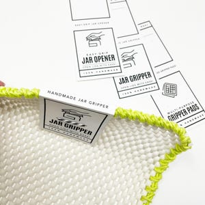 K&ouml;nnte beinhalten: Handgefertigter wei&szlig;er und gr&uuml;ner Einmachglas-Greifpad mit einem schwarz-wei&szlig;en Etikett mit der Aufschrift "Jar Gripper Open lids with ease! 100% Handmade".