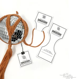 Op de afbeelding: Een bruine en zilveren discobal-zonenvanger met een bruine kwast die eraan hangt. De zonenvanger is handgemaakt en wordt geleverd met een wit label waarop staat "Hanging Suncatcher 100% Handmade".