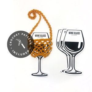 May include: A crocheted wine glass holder with a strap. The holder is orange and has a woven pattern. The image also shows a black and white illustration of a wine glass with the text "Wine Glass Holder".